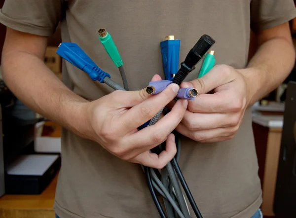 Un informaticien tient dans ses mains un bouquet des câbles — Photo