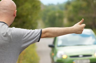 Bald-headed man hitching on road clipart