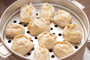 Uncooked oriental dumplings on metal steam cooker clipart
