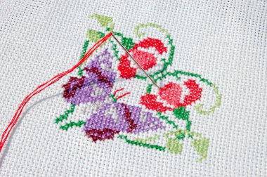 Needlework. Cloth with needle, thread and batterfly, which was embroidered by cross-stitch method clipart