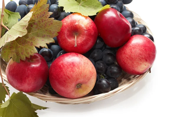 Frutos frescos: uvas e maçãs em prato de vime — Fotografia de Stock
