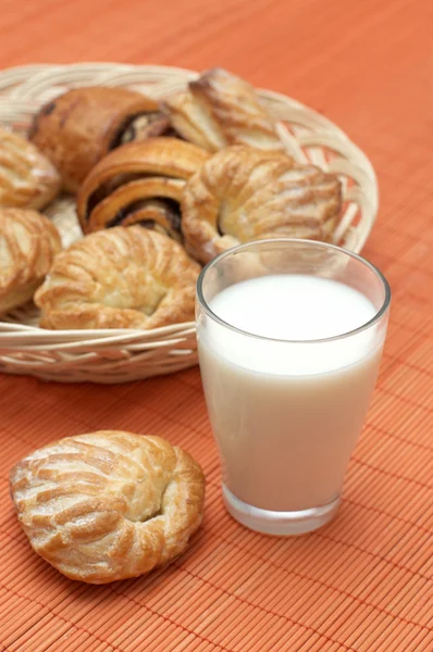 stock image Glass with fresh milk and puff pastry on bamboo place mat