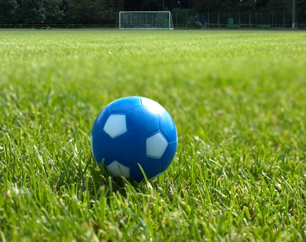 バック グラウンドで目標に対して小さい青サッカー ボール — ストック写真