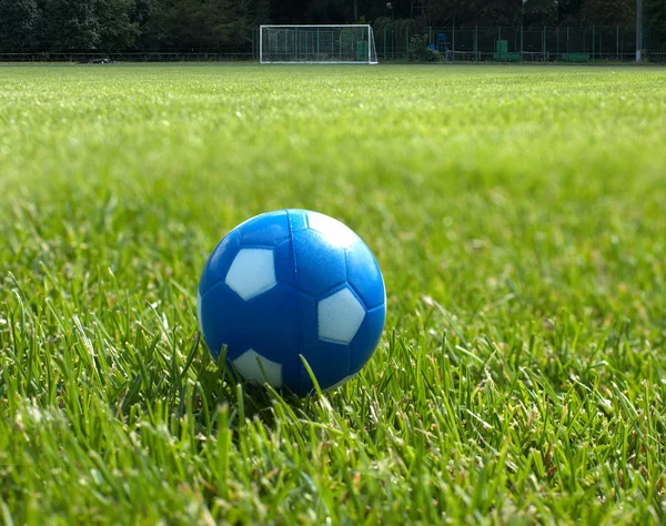 Bola de futebol azul pequena contra gol no fundo — Fotografia de Stock