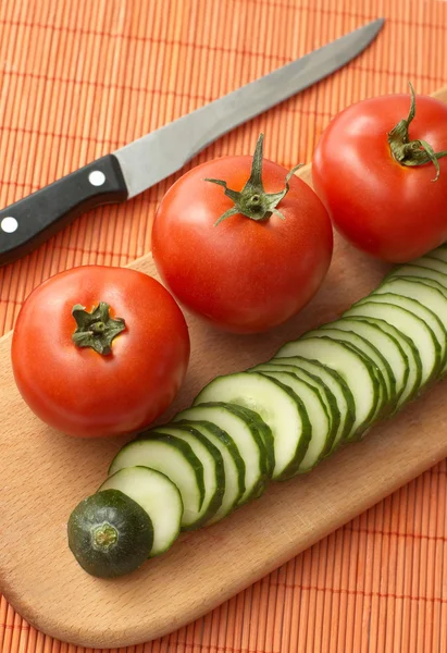 stock image Cooking: tomatoes, cucumber and knife on kitchen board