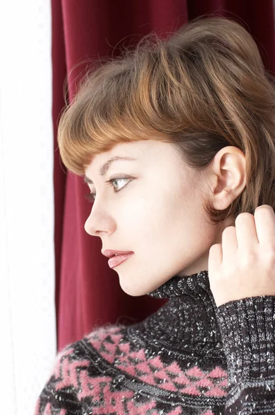 stock image Young beautiful woman staing near dark curtain and looking into window