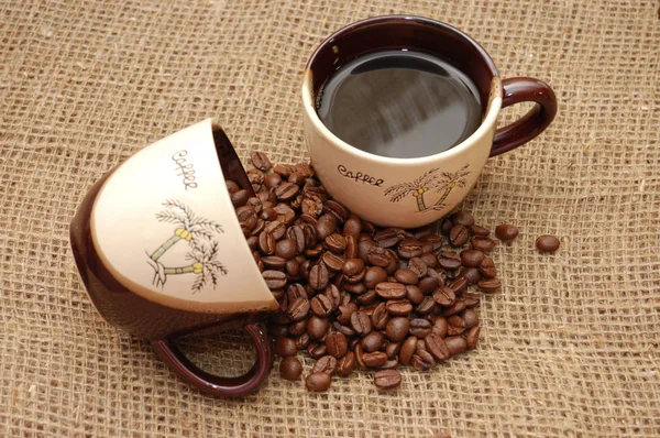 Dwie filiżanki kawy: jeden z napojów i innych z fasoli — Zdjęcie stockowe