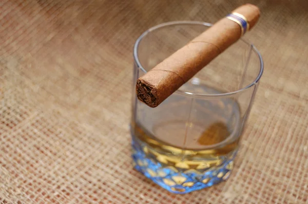 Кубинская сигара на стекле с виски — стоковое фото