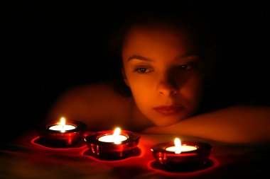 Woman looking on three candles clipart