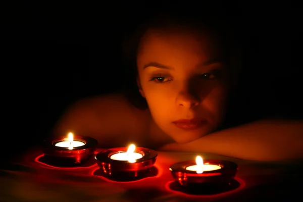 Frau blickt auf drei Kerzen Stockbild