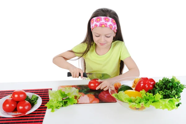 Klein meisje gesneden tomaten aan de tafel — Stockfoto