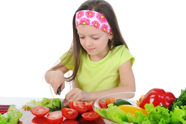 Klein meisje gesneden tomaten aan de tafel — Stockfoto