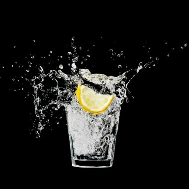 Splash in a glass with lemon and ice on a black background clipart