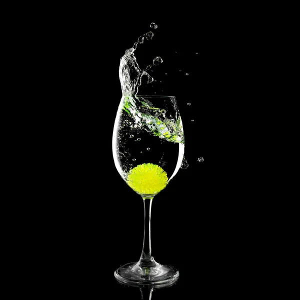 Splash em um copo com bola de limão e gelo em um fundo preto — Fotografia de Stock