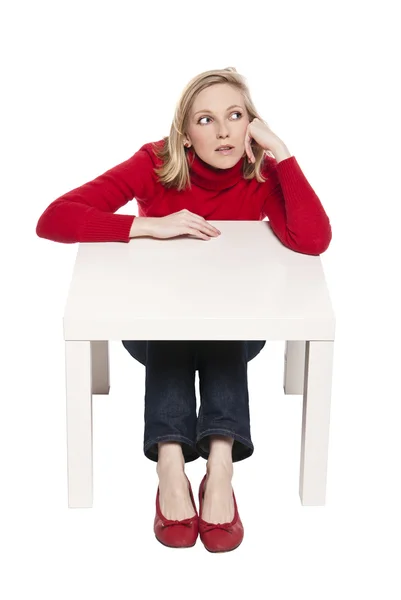 Młoda kobieta siedząca w śmieszne małe biurko — Zdjęcie stockowe