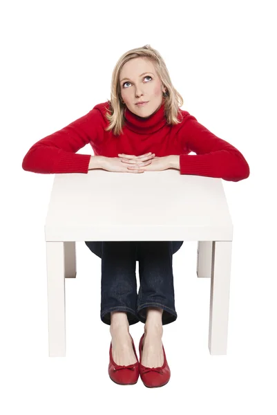 Młoda kobieta siedząca w śmieszne małe biurko — Zdjęcie stockowe