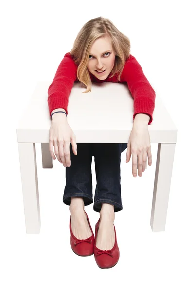 Jovem mulher sentada na pequena mesa engraçada — Fotografia de Stock