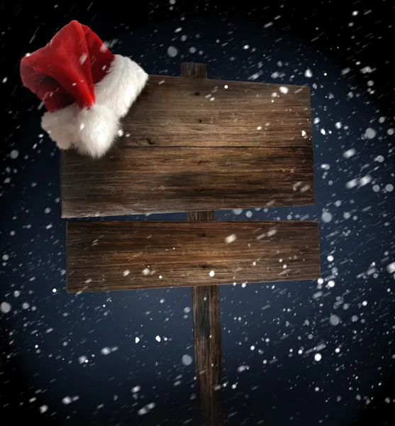 Ξύλινη ταμπέλα με καπέλο santa σε χιονισμένο φόντο — Φωτογραφία Αρχείου
