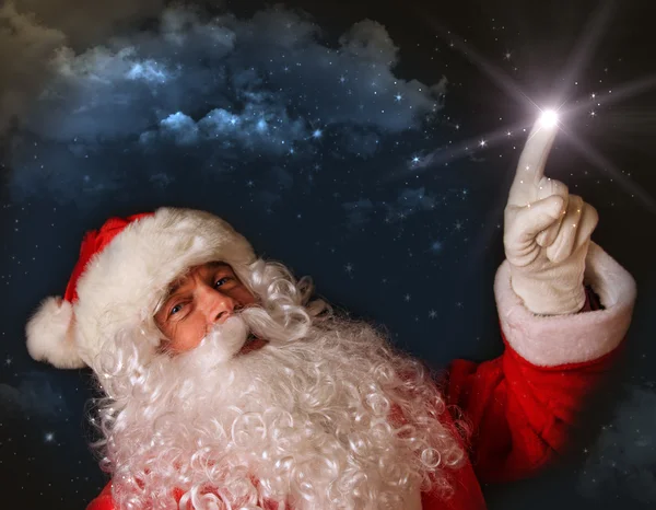 圣诞老人与魔法的光芒指向天空 — 图库照片