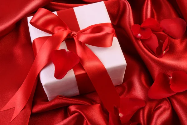 Red ribbon holiday gift on satin — Stock Photo, Image