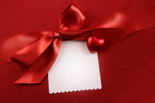 Arco de cetim e cartão branco para presente no vermelho — Fotografia de Stock