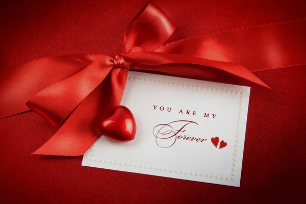 Arco rojo y tarjeta blanca para regalo sobre fondo satinado —  Fotos de Stock