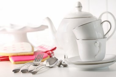 Porcelian teapot with cups and valentine cookies in background clipart