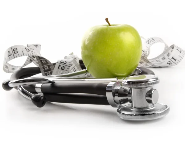 Grüner Apfel mit Stethoskop auf weiß — Stockfoto