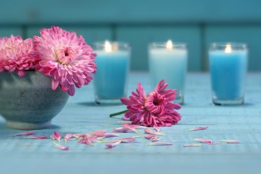 Pink chrysanthemum flowers in bowl of water with candles clipart