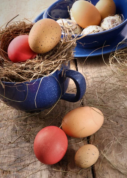 Huevos de Pascua en taza de esmalte azul con paja — Foto de Stock