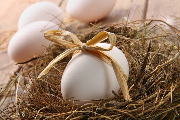 Beyaz yumurta yuvada ahşap saman yay ile — Stok fotoğraf