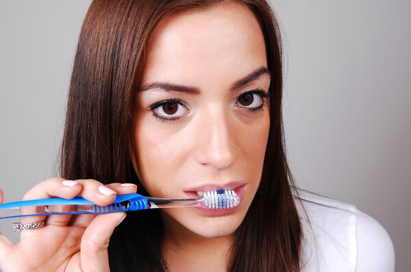 A young brunette woman brushing her teeth wit a toothbrush as a normal routine after a dinner.