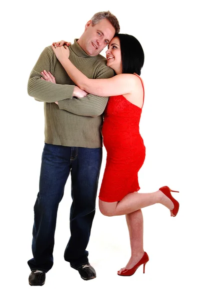 中高年カップルでは 彼女の赤いドレスと黒い髪を与える彼女の夫白い背景の上の彼の側に立って 大きな抱擁 — ストック写真