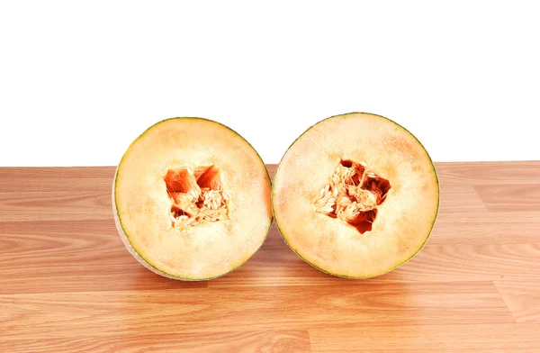 两个一半里面坐在木板为白色背景上的种子的哈密瓜 — 图库照片