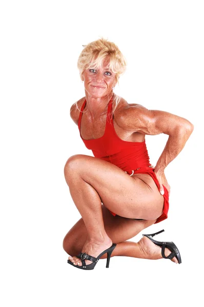 Blond Bodybuilding Girl Kneeling Studio Red Dress Shooing Her Very — Stock Photo, Image