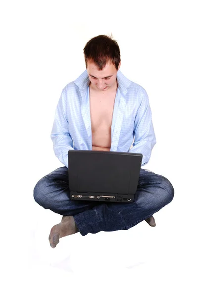 坐在地板上有一台笔记本电脑 在他的膝盖和开放的蓝色礼服衬衫 孤立的白色背景上一个十几岁的年轻男人 — 图库照片