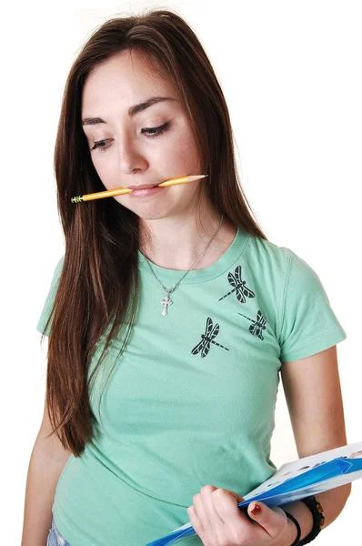 在绿色的 恤和一支铅笔在她的嘴 长时间棕色的头发 站在工作室为白色背景的漂亮少年 — 图库照片