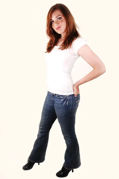 白のトップとジーンズ Shooing 彼女の明るい赤い髪のスタジオで立っているハイヒールの背の高い素敵な — ストック写真