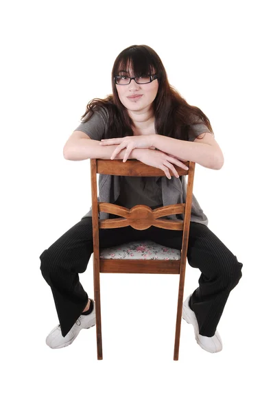 一个年轻的女孩坐在一把旧椅子 戴着眼镜 为白色背景上倒退 — 图库照片