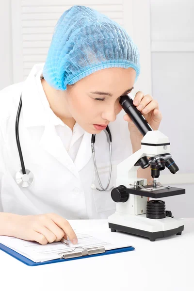 Медицинская - медсестра, смотрящая в микроскоп — стоковое фото