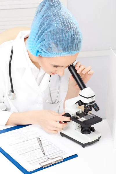 Медицинская - медсестра, смотрящая в микроскоп — стоковое фото