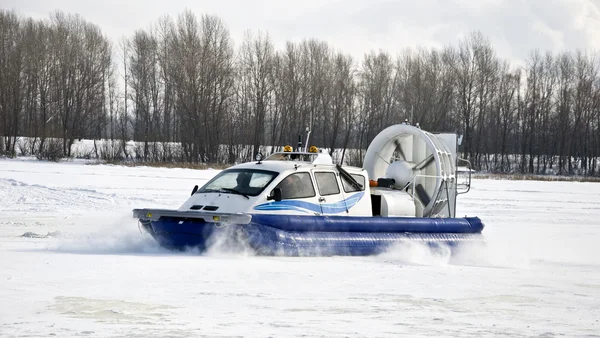 stock image Hovercraft rides on the frozen river, picking up snow dust. Winter