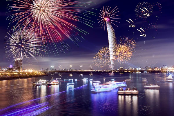 stock image Fireworks firing up into the sky with a boat on a river below them, with a reflection on the water