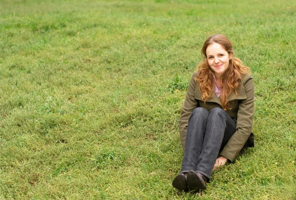Redhead vrouw zitten op het gras — Stockfoto