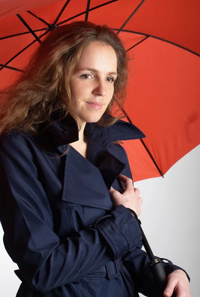 Vöröshajú nő alatt piros esernyő — Stock Fotó