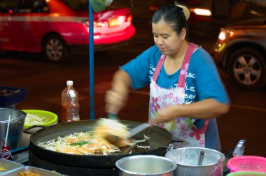 BANGKOK - MARCH 03: Street cook woman preparing phat thai noodle clipart