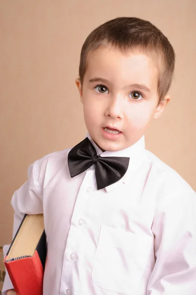 Pequeno nerd menino em gravata arco com livro — Fotografia de Stock
