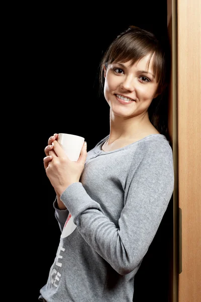 Kvinna i pyjamas lutande dörröppningen — Stockfoto