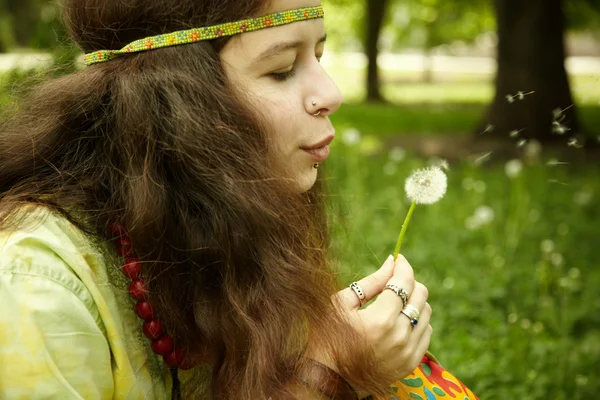 Молодая женщина, дующая одуванчик — стоковое фото