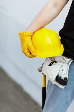 Builder with yellow helmet and working gloves on building site clipart